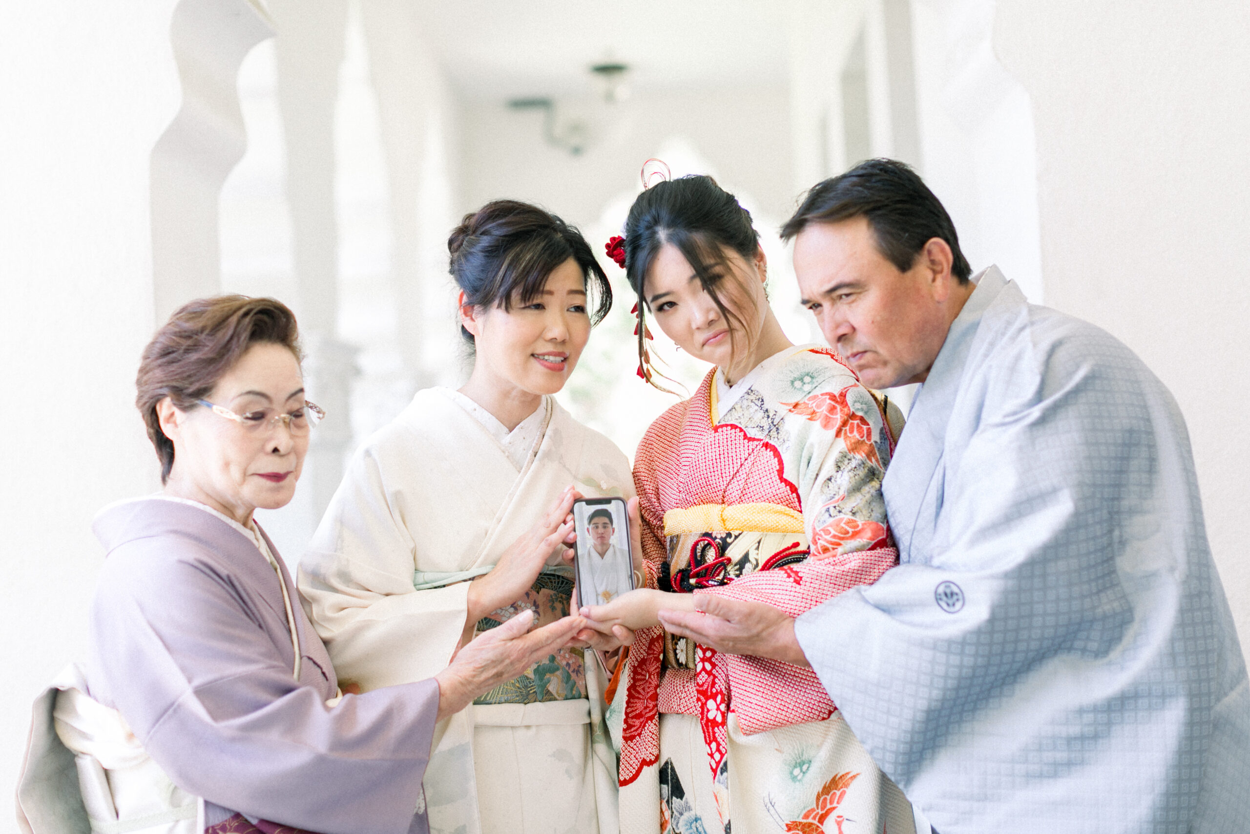 Grandmother, parents, and daughter in formal kimono holding a smartphone photo of the coming-of-age son during a Seijinshiki kimono session in Los Angeles.