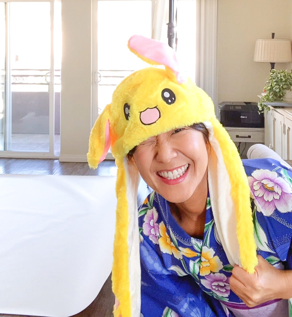 七五三の撮影現場で、3歳の子どもを安心させるために黄色い帽子をかぶる着付け師